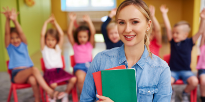 teacher holding book with children in the background
