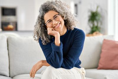 Smiling middle aged lady posing in living room at home.