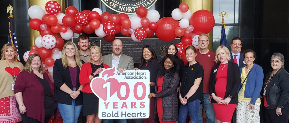 Group of adults standing around a sign celebrating 100 years of the American Heart Association