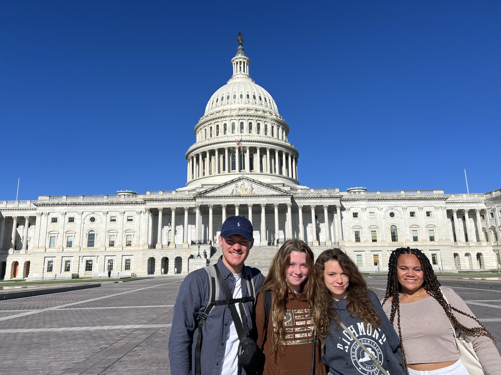 Three female youth and one young male standing in front of the US Capitol