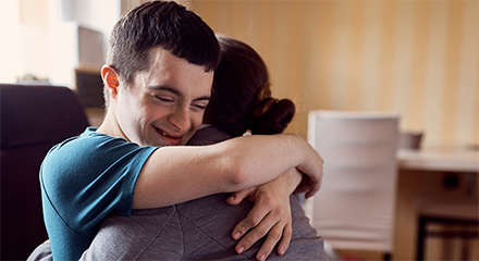 Young man smiling and hugging his caregiver