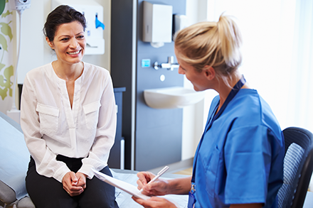 A patient talks with her doctor while her doctor takes notes.