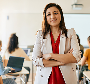 A teacher smiles confidently with her arms crossed.