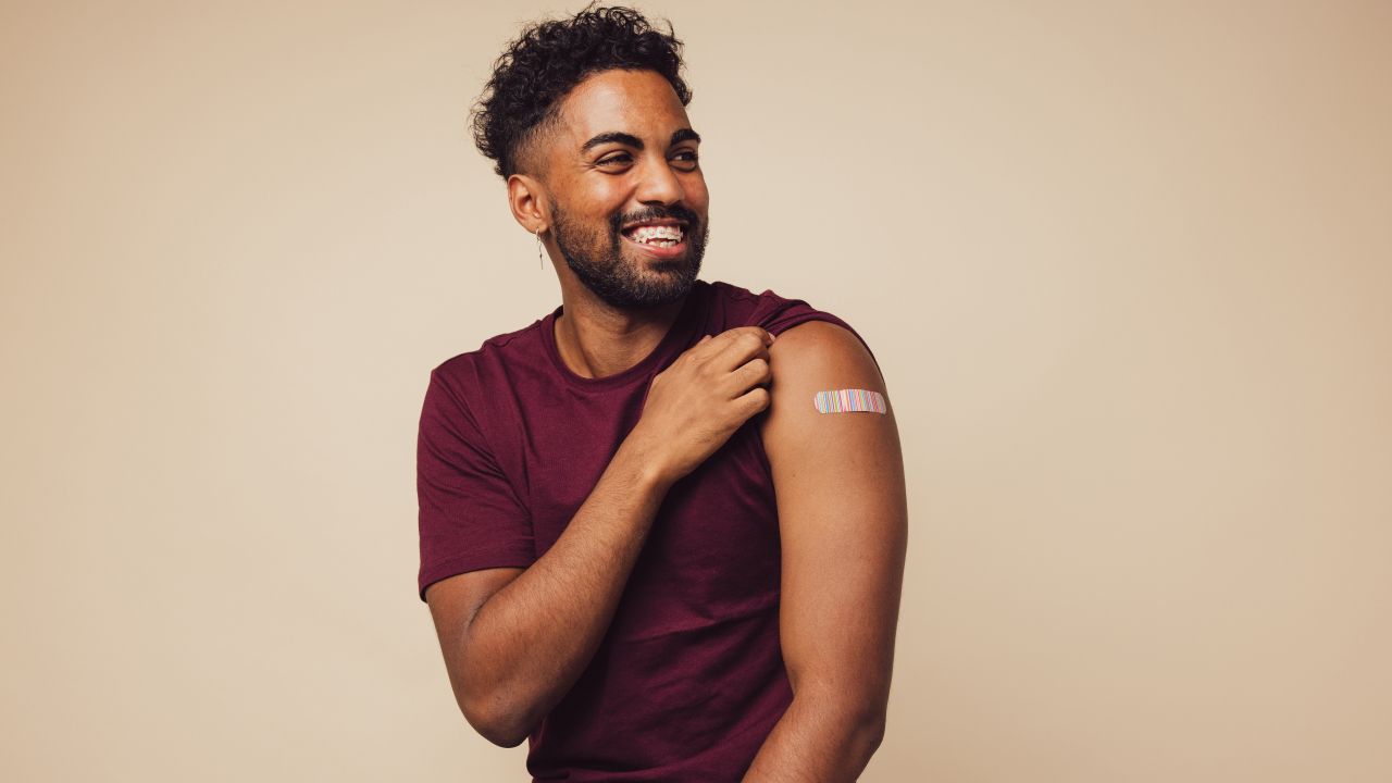 A young man shows off the bandage on his arm from getting vaccinated.