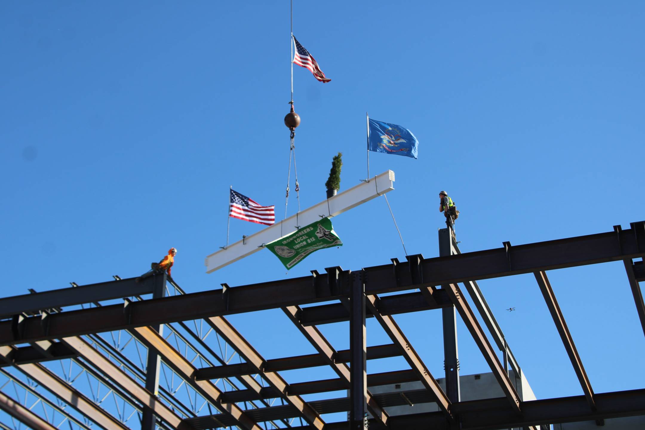 Two workers wait atop the lab's structure as a crane lowers the final beam into place