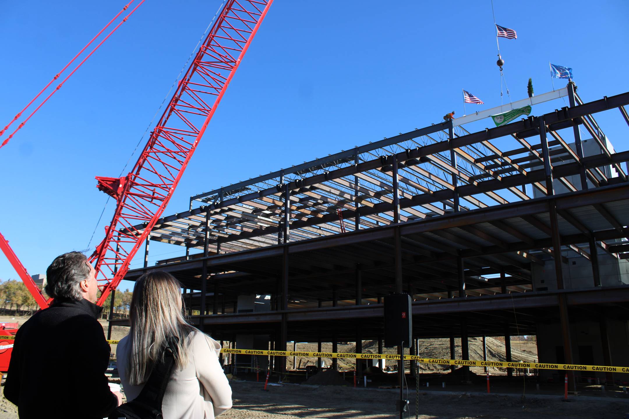 Governor Burgum and his secretary watch as the final beam is put into place