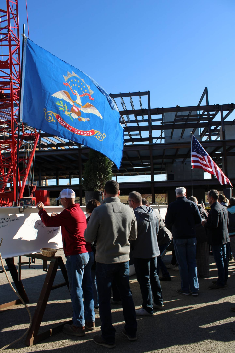 Team ND employees sign the final beam under the North Dakota state flag