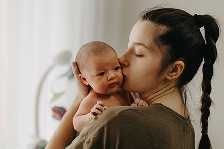 A mother kisses her newborn baby.