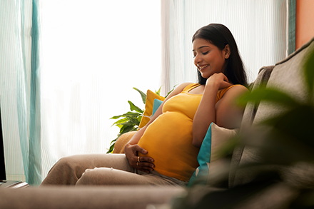 A pregnant young woman smiles as she lovingly cradles her pregnant belly