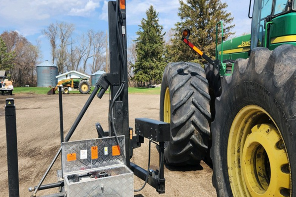 John Deere tractor at a farm with a portable lift next to the cab.