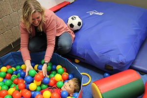 Image of child in a container of colored balls used for sensory processing