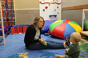 Therapist on the floor with a child practicing speech sounds