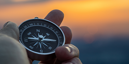 Compass being held against a sunset.