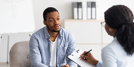 A man calmly visiting with a provider while she takes notes.