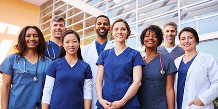 Several providers standing together, smiling, in front of a medical center.