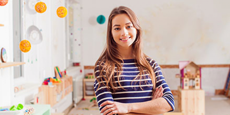 Female preschool teacher holding books in a classroom