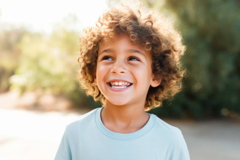 young child with brown curly hair smiling